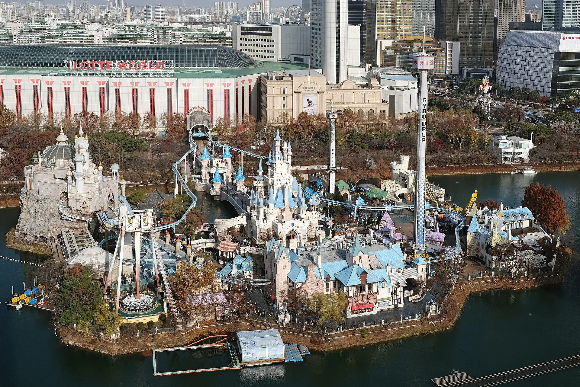 Aerial view of Lotte World's Magic Island castle on Seokchon Lake with the indoor dome and Seoul skyline behind