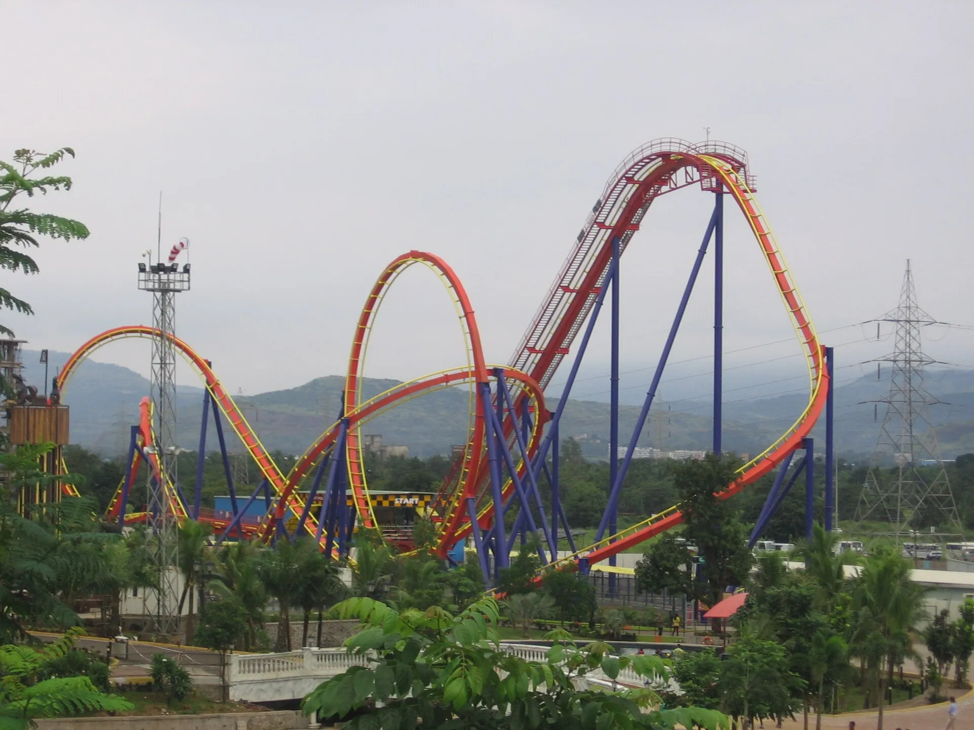 Nitro roller coaster at Imagicaa theme park Khopoli with red track, blue supports and the Sahyadri hills behind