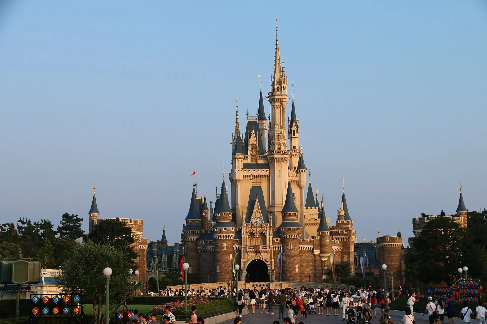 Cinderella Castle at Tokyo Disneyland at golden hour with visitors on the plaza