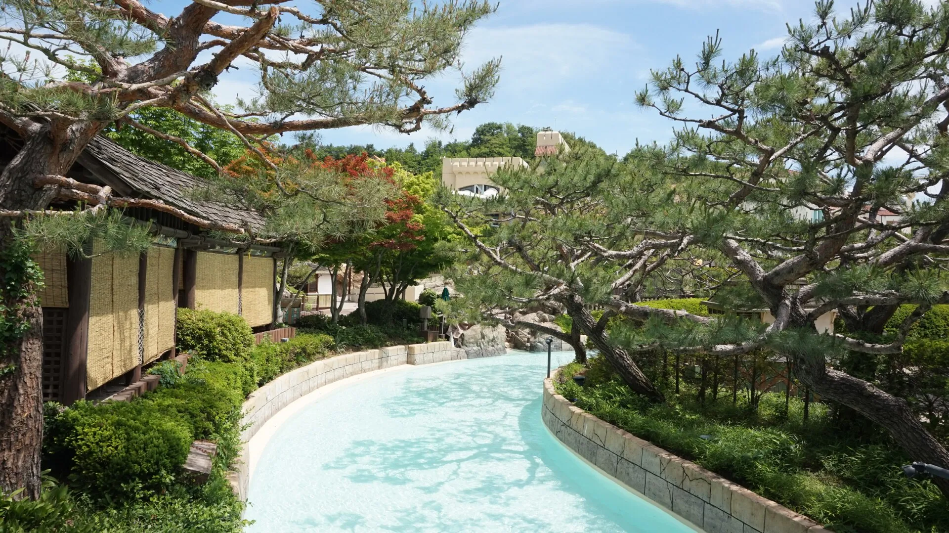 Lazy river winding past pine trees and thatched cabanas at Caribbean Bay water park in Yongin, South Korea