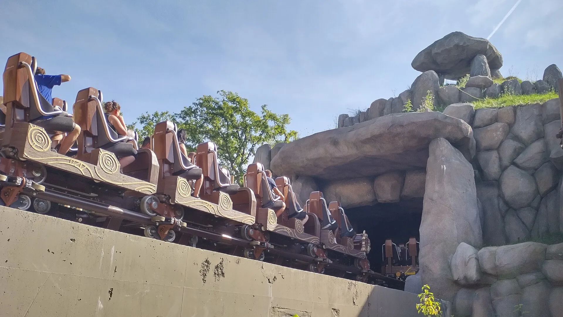 Toutatis roller coaster train climbing past themed rockwork at Parc Astérix