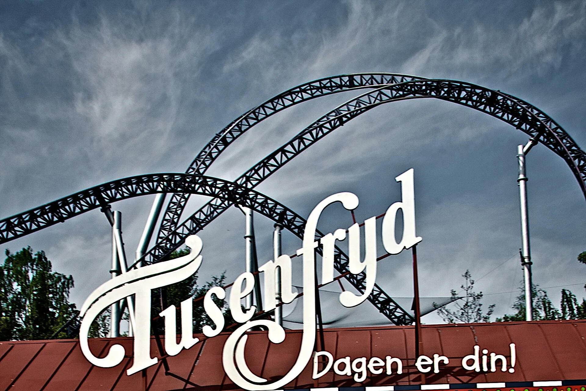 TusenFryd entrance sign with the SpeedMonster roller coaster track arching behind it