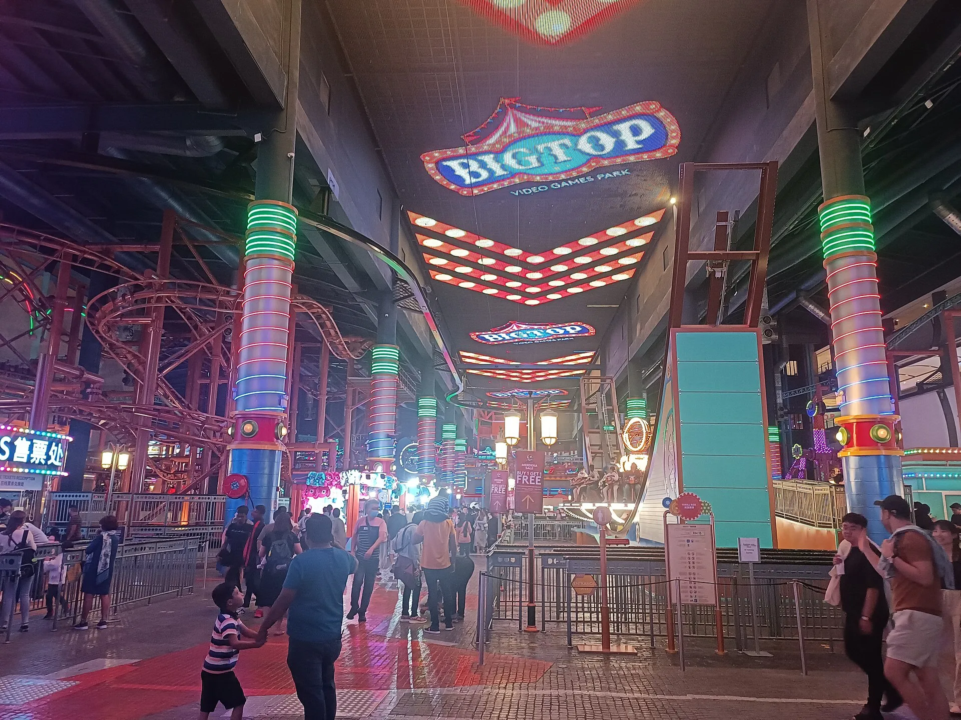 Neon-lit ride floor of Skytropolis Indoor Theme Park at Resorts World Genting with coaster track and illuminated columns